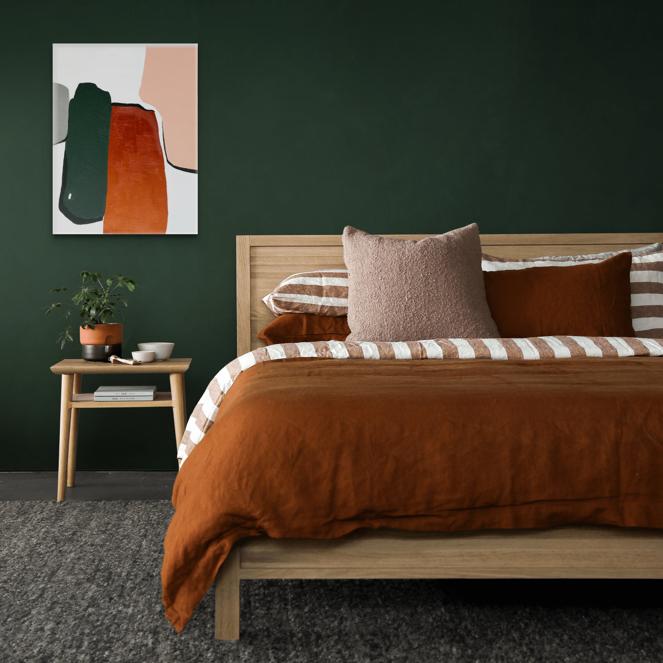 A painting titled 'Anti Gravity - #2' displayed above a bed in a room with dark green walls, the artwork features abstract shapes in orange and black.
