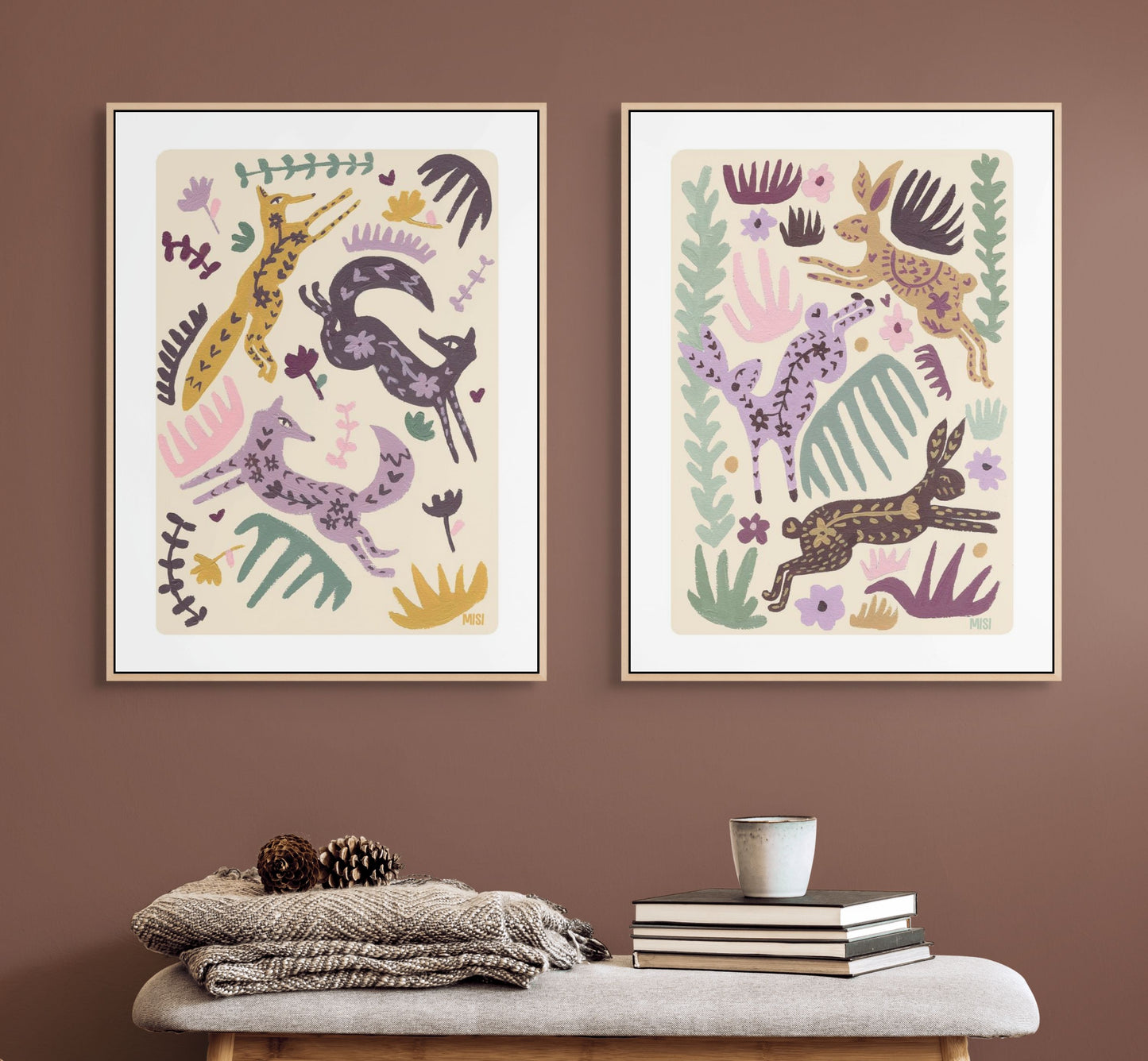 Two framed abstract animal artworks on a brown wall with a bench and books below.